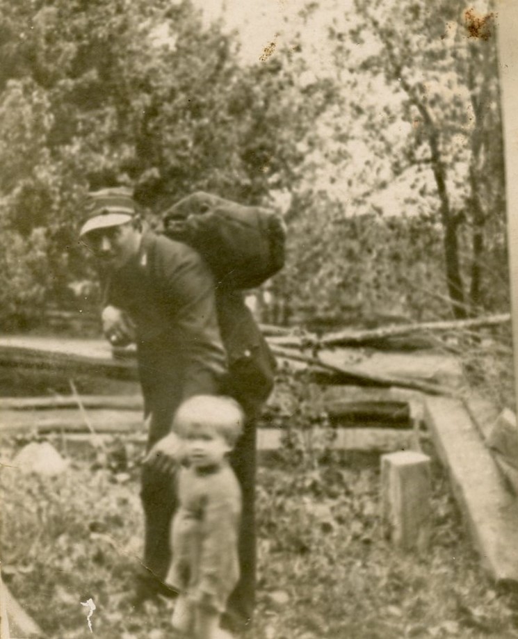 Fotografia w sepii Waclawa Buskiego w czapce i plecakiem trzymającego syna Adrzeja za rekę