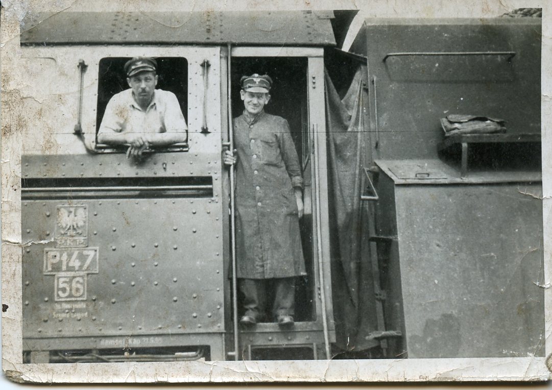 Fotografia czarno-biała przedstawiająca fragment lokomotywy. Dwie postaci mężczyzn. Wacław Buski jako maszynista.