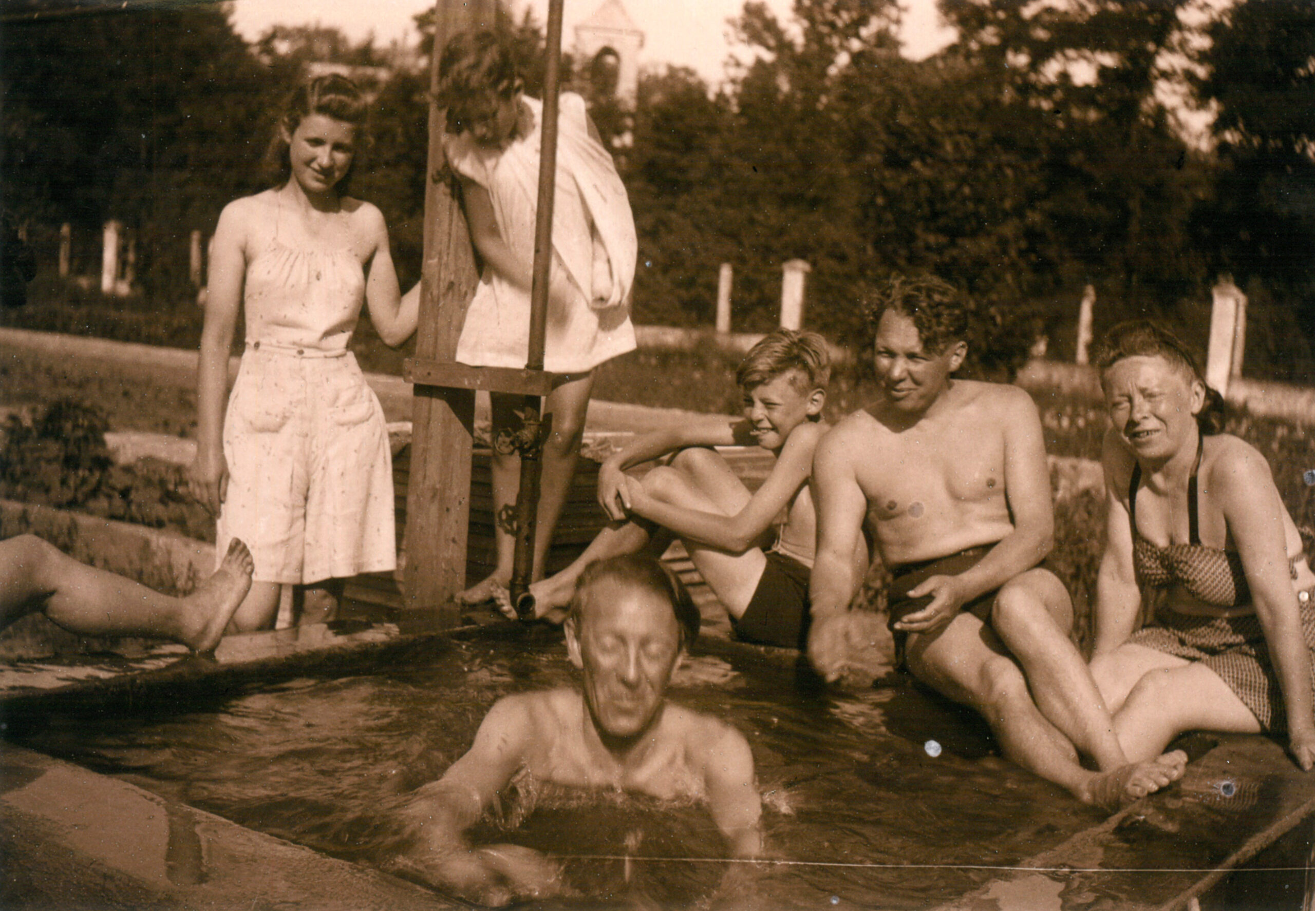Pięć osób pozujących do zdjęcia, jedna w basenie.