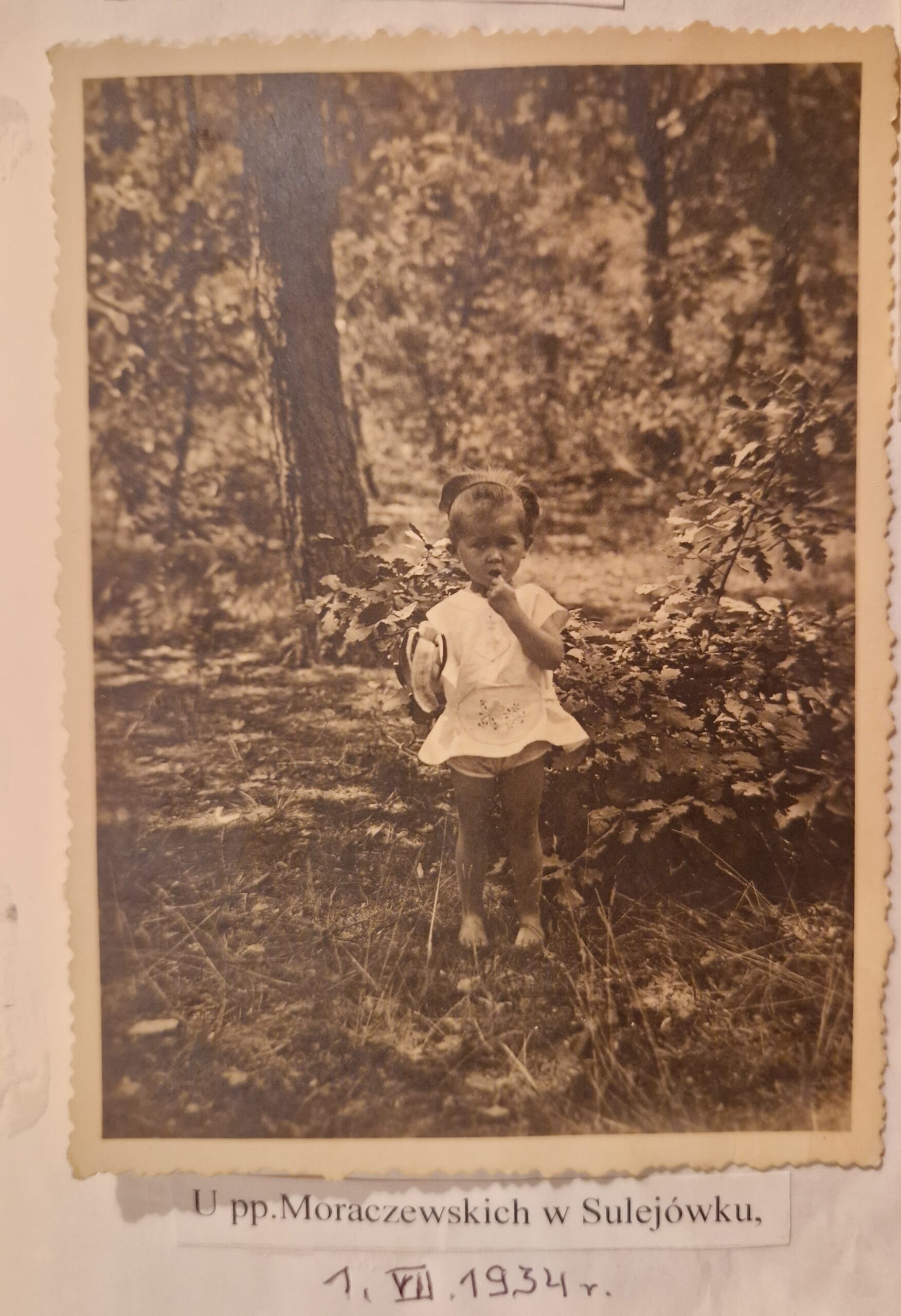 dziewczynka trzymająca w reku banana stoi w ogrodzie